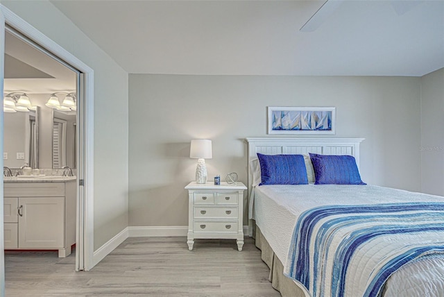 bedroom with light wood-style floors, baseboards, and ensuite bathroom