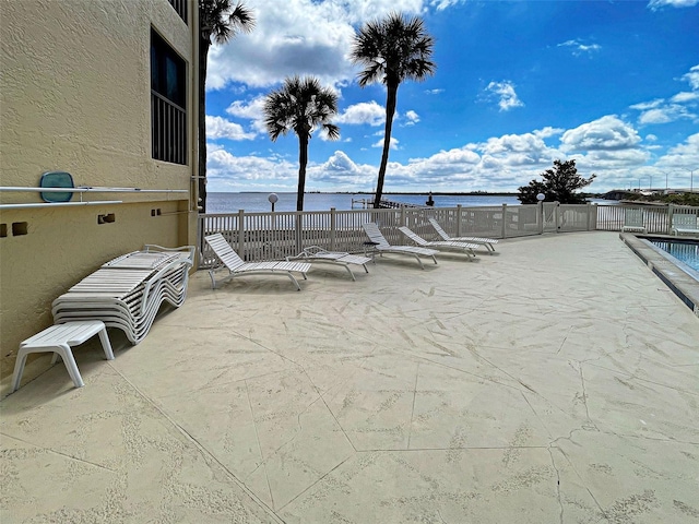 view of patio / terrace with a water view and fence