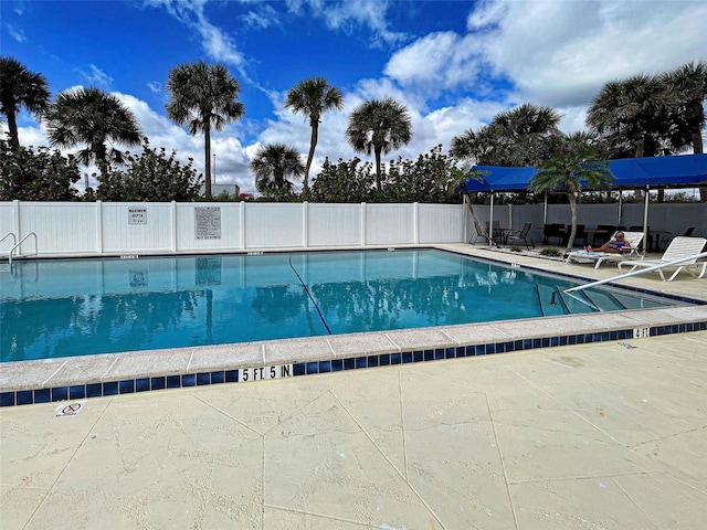 community pool with fence and a patio