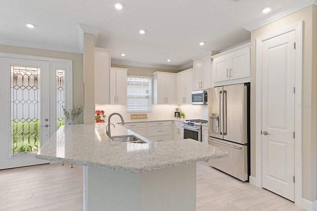 kitchen with premium appliances, backsplash, a peninsula, white cabinetry, and a sink