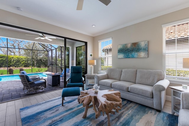 living area with ceiling fan, ornamental molding, wood finished floors, and a sunroom