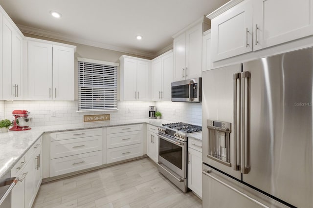 kitchen featuring tasteful backsplash, light stone counters, appliances with stainless steel finishes, crown molding, and white cabinetry