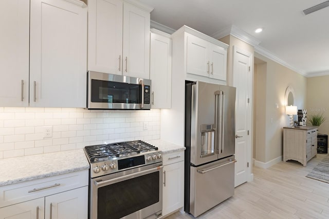 kitchen with stainless steel appliances, visible vents, backsplash, ornamental molding, and white cabinetry