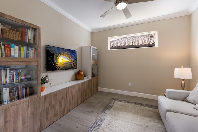 living area featuring ornamental molding, ceiling fan, baseboards, and wood finished floors