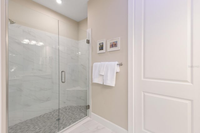 bathroom with marble finish floor, a marble finish shower, and baseboards