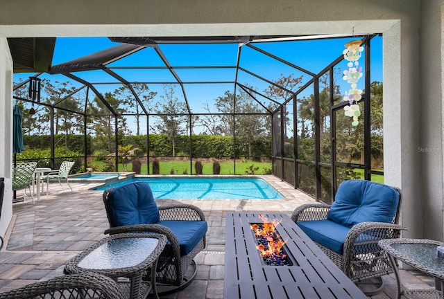 view of swimming pool featuring glass enclosure, a patio area, a pool with connected hot tub, and a fire pit