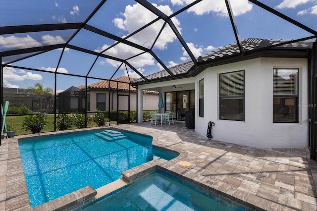 view of swimming pool featuring ceiling fan, a patio, a lanai, and a pool with connected hot tub