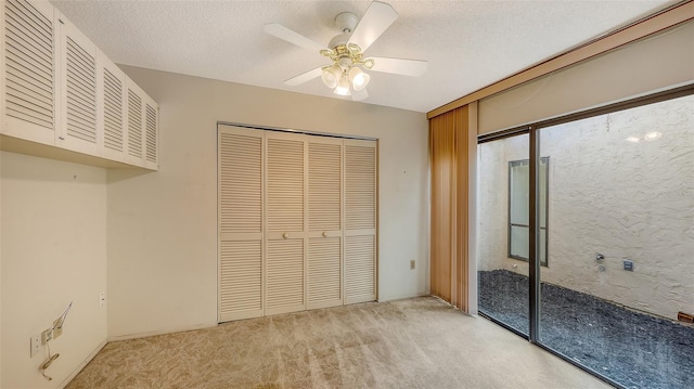 unfurnished bedroom with a closet, light carpet, ceiling fan, and a textured ceiling