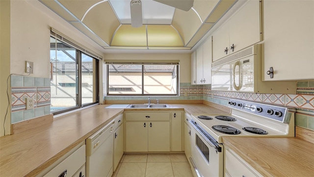 kitchen featuring white appliances, decorative backsplash, light countertops, a sink, and light tile patterned flooring