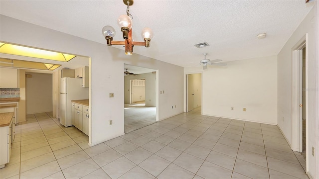 empty room featuring visible vents, ceiling fan, a textured ceiling, and light tile patterned floors