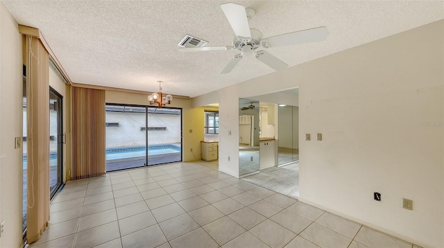 empty room with light tile patterned floors, visible vents, a textured ceiling, and ceiling fan with notable chandelier