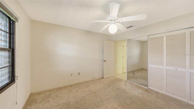 unfurnished bedroom featuring light colored carpet, a closet, visible vents, and a textured ceiling