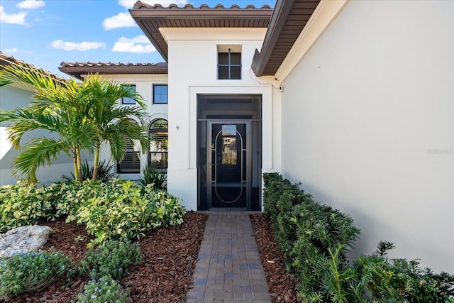 entrance to property with a tiled roof and stucco siding