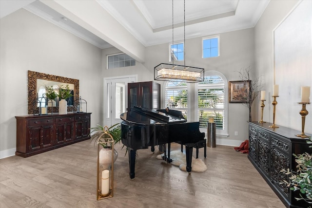 living area with crown molding, baseboards, a raised ceiling, and wood finished floors