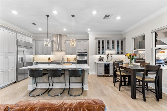 kitchen with visible vents, wall chimney exhaust hood, wine cooler, appliances with stainless steel finishes, and gray cabinets