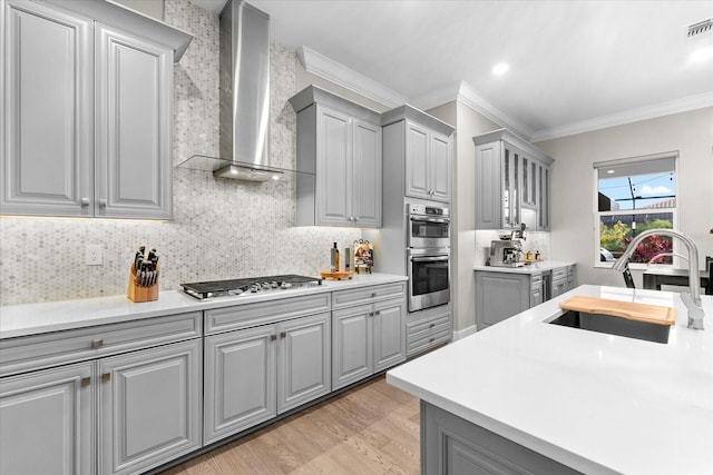 kitchen featuring wall chimney exhaust hood, gray cabinets, and stainless steel appliances