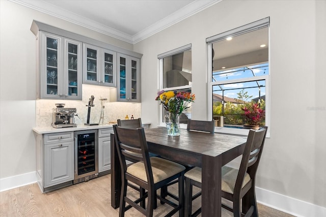 dining area with light wood-style floors, baseboards, wine cooler, and ornamental molding