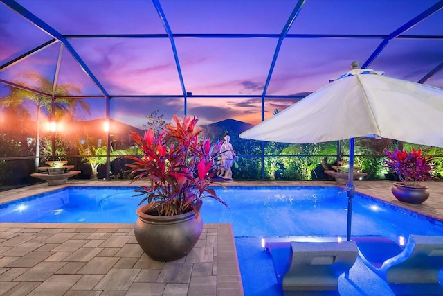 view of swimming pool featuring a patio area, a pool with connected hot tub, and glass enclosure