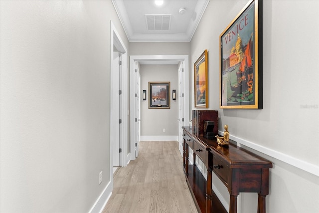 hallway featuring light wood-style floors, visible vents, crown molding, and baseboards