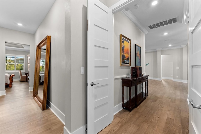 corridor with baseboards, visible vents, crown molding, light wood-type flooring, and recessed lighting