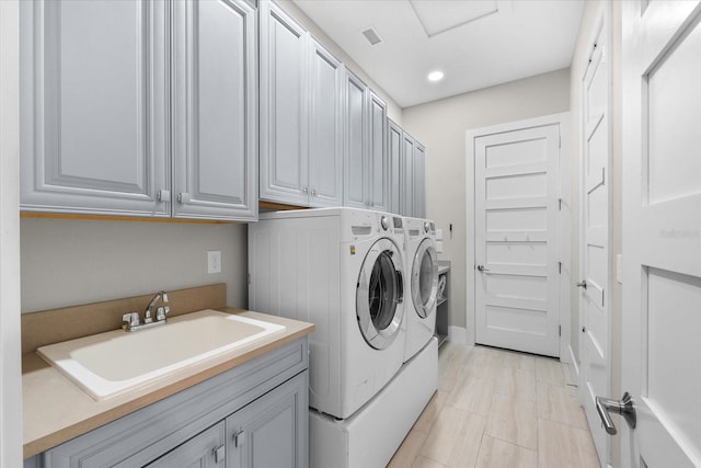 laundry room with visible vents, separate washer and dryer, a sink, and cabinet space