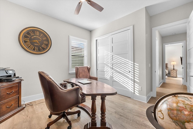 office space with light wood-style floors, ceiling fan, and baseboards