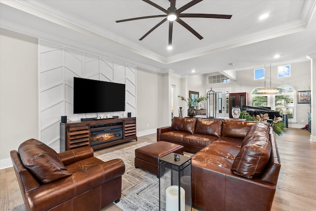 living area with light wood-style flooring, ornamental molding, baseboards, and a glass covered fireplace