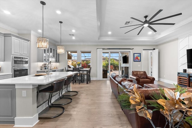 living area featuring light wood-style floors, a ceiling fan, visible vents, and crown molding