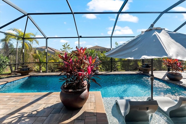 outdoor pool featuring glass enclosure and a patio