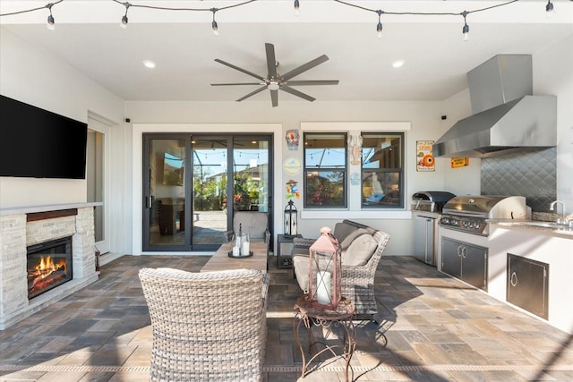 view of patio featuring area for grilling, exterior kitchen, a fireplace, and a ceiling fan