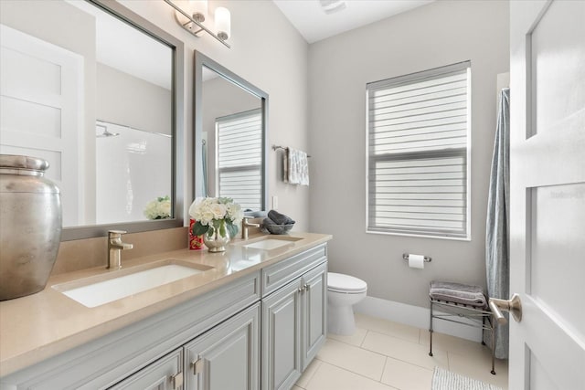 bathroom featuring toilet, double vanity, a sink, and tile patterned floors