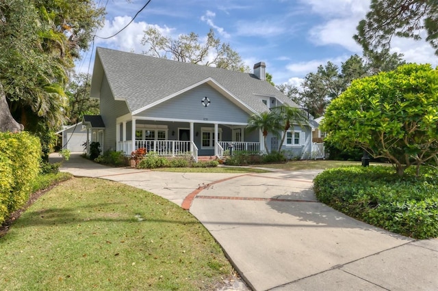 view of front of property featuring a porch, a front lawn, a chimney, and a shingled roof