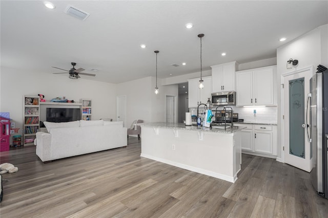 kitchen with wood finished floors, visible vents, white cabinetry, open floor plan, and appliances with stainless steel finishes