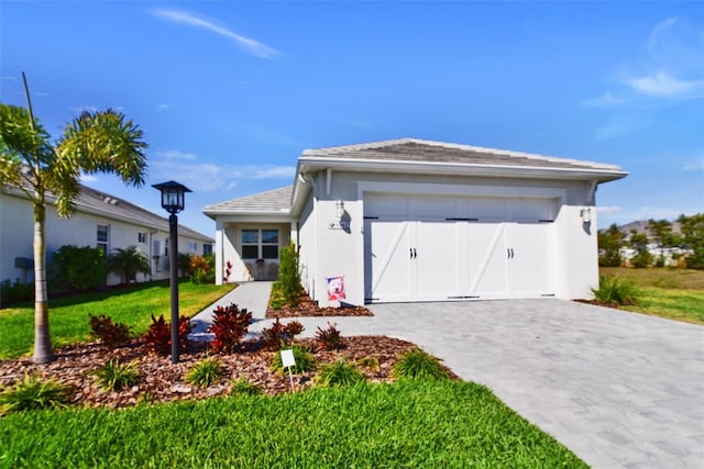 view of front of home with a garage, a front lawn, decorative driveway, and stucco siding