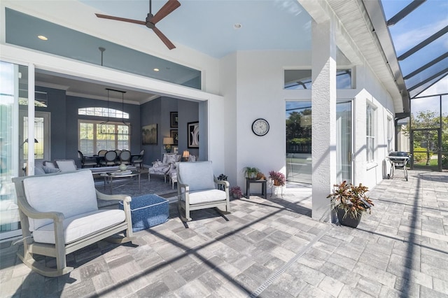 view of patio featuring glass enclosure, ceiling fan, and an outdoor hangout area