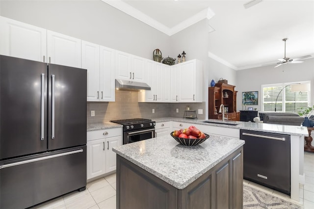 kitchen featuring under cabinet range hood, a peninsula, a sink, high quality appliances, and crown molding