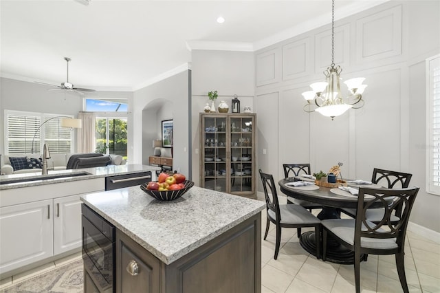 kitchen with crown molding, a decorative wall, a kitchen island, a sink, and dishwasher