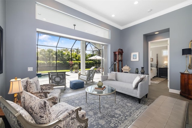 living area with baseboards, a sunroom, wood finished floors, crown molding, and recessed lighting