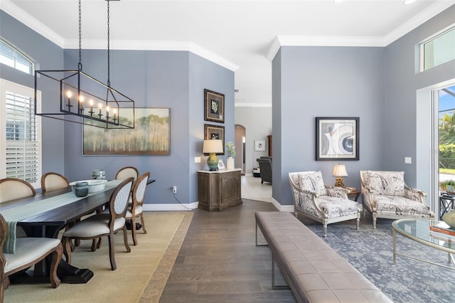 dining area featuring arched walkways, crown molding, baseboards, and wood finished floors