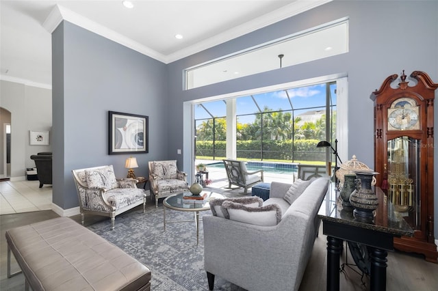 living room with a sunroom, baseboards, ornamental molding, and arched walkways