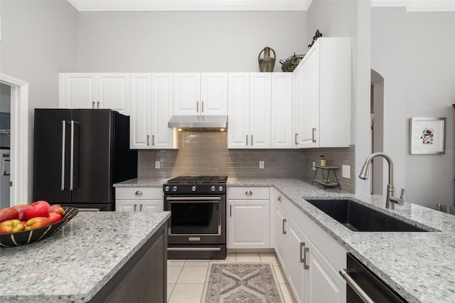 kitchen featuring decorative backsplash, light tile patterned flooring, a sink, under cabinet range hood, and black appliances