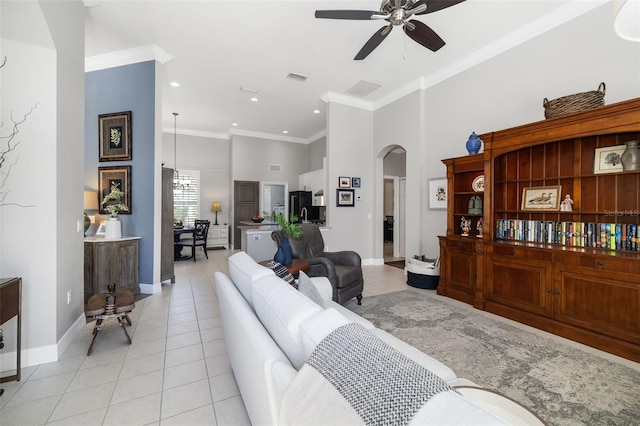 living area featuring light tile patterned floors, baseboards, arched walkways, ornamental molding, and a high ceiling