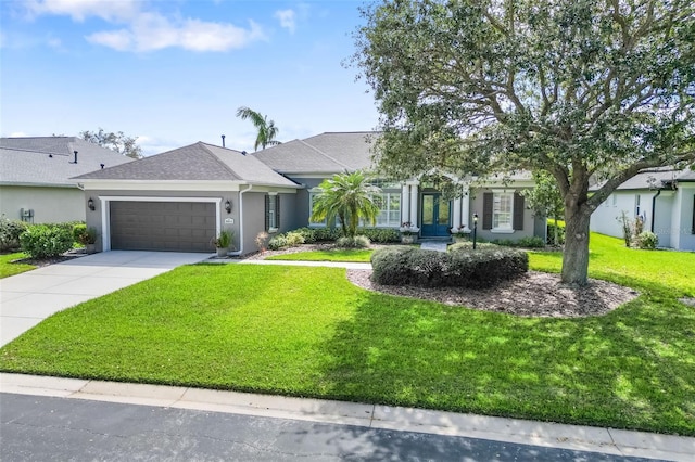 view of front of house with an attached garage, a front lawn, concrete driveway, and stucco siding