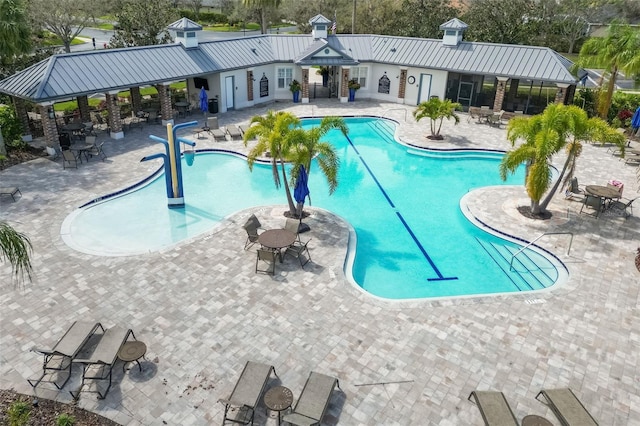 pool with a patio area, fence, and a water play area