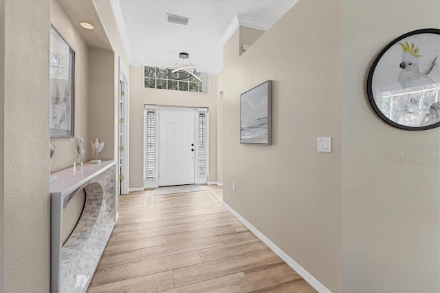 entryway featuring baseboards, wood tiled floor, visible vents, and crown molding