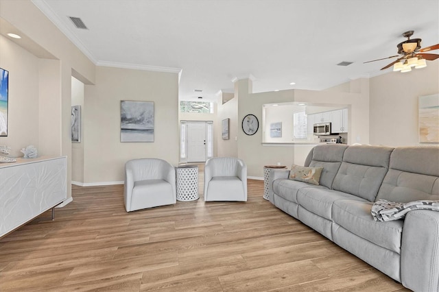 living area featuring light wood-style floors, visible vents, crown molding, and baseboards