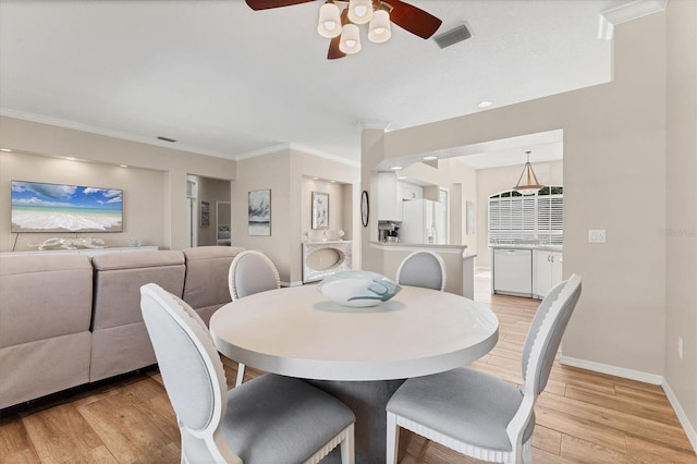 dining space with light wood-style floors, visible vents, baseboards, and ornamental molding