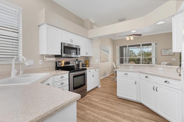 kitchen with appliances with stainless steel finishes, light wood-type flooring, light countertops, and a sink