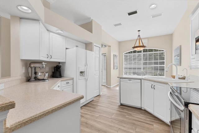 kitchen featuring white appliances, a sink, visible vents, white cabinets, and light wood-type flooring