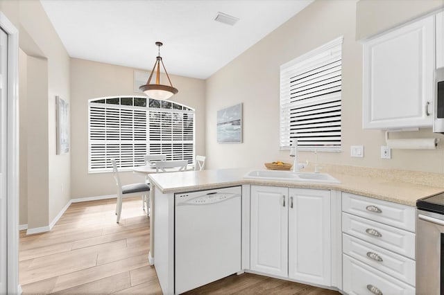 kitchen with light wood-type flooring, white cabinets, white dishwasher, and a sink